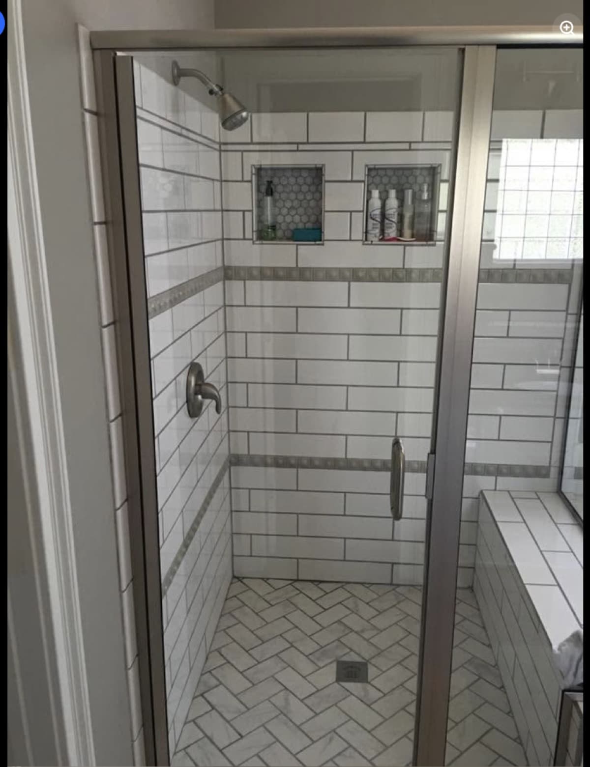 Frameless glass walk-in shower with subway tile and herringbone floor