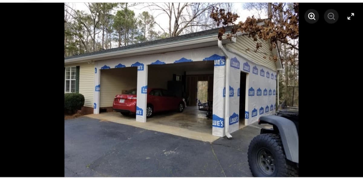 Detached garage addition under construction with house wrap